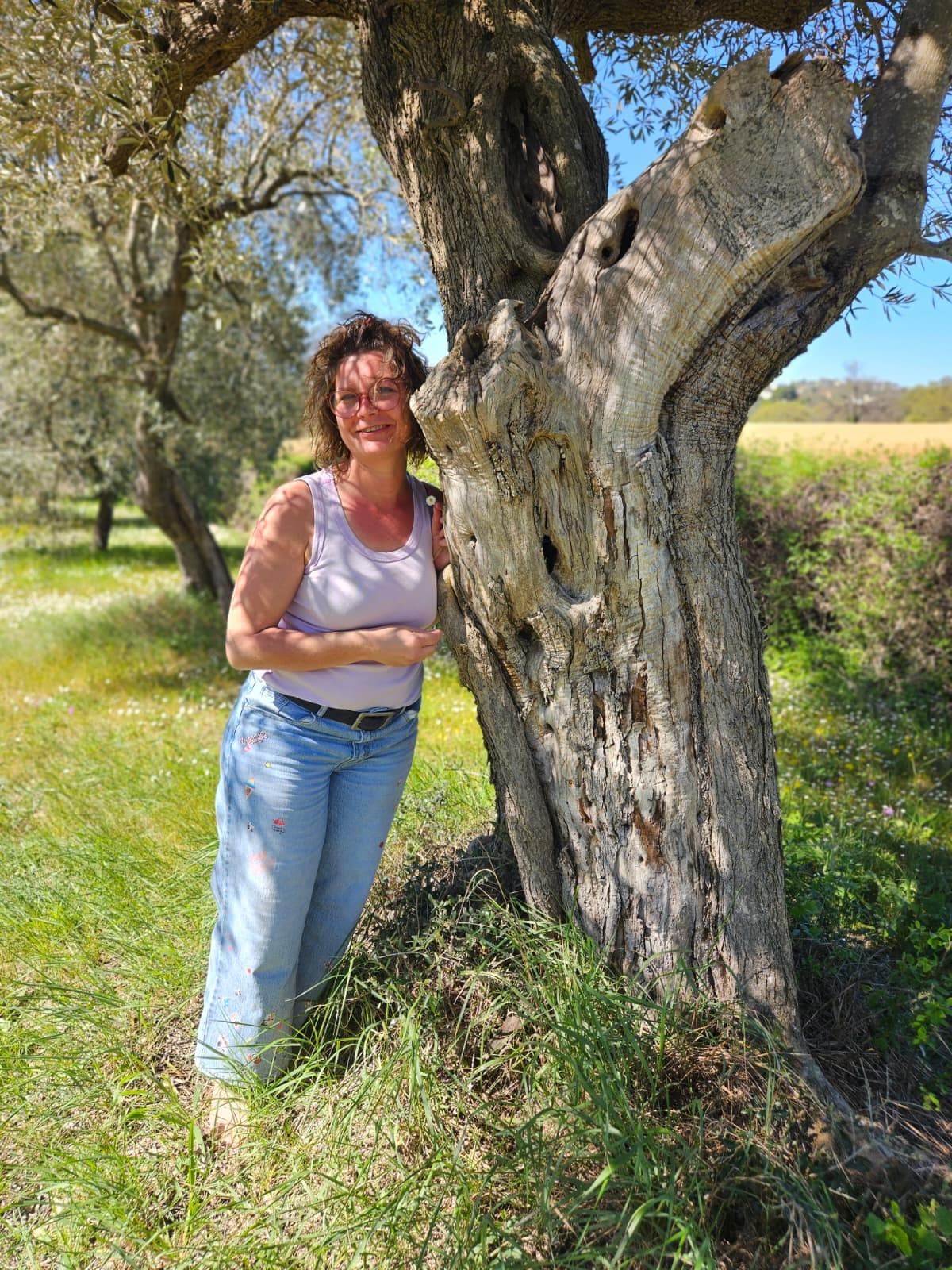 Marion Röttger in naturnaher Umgebung neben einem alten Baum